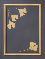 dry colored decorative leaves and golden photo frame on gray background