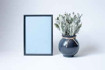 black photo frame and decorative vase on a white background with copy space