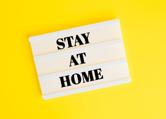 The inscription stay home on a lightbox on a yellow background. Quarantine, coronavirus concept