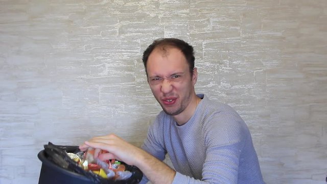 Crazy man delves into the bin that stinks.