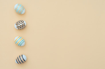Decorated Easter eggs lie on the yellow background. Happy Easter holiday and minimalism concept. Greeting, invitation card. Flat lay style with copy space.