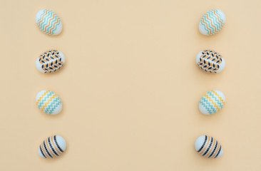 Fototapeta premium Decorated Easter eggs lie on the yellow background. Happy Easter holiday and minimalism concept. Greeting, invitation card. Flat lay style with copy space.