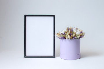 black photo frame and decorative arrangement of dried flowers on a white background with copy space