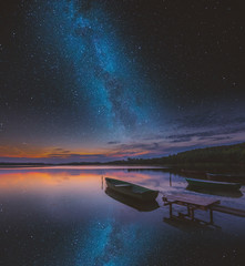 Surreal lake with boats under starry sky