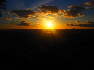 Puesta de sol amarillenta y nubosa en las montañas frente a Madrid