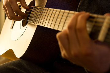 Man plays the guitar with warm light close up