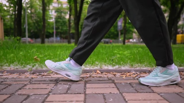 panorama from feet to face man in casual trendy clothes and sneakers walking on the street in urban city slow motion