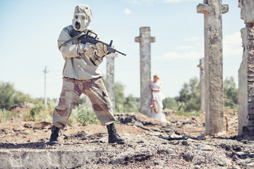Soldier in the gas mask with the rifle on the foreground, girl in white with the doll near cross on the background