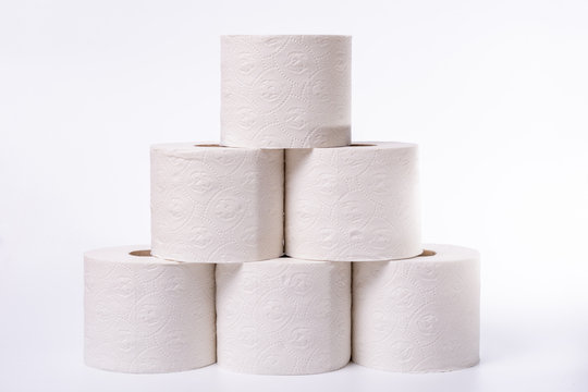 Lots of toilet paper rolls piled up on white background