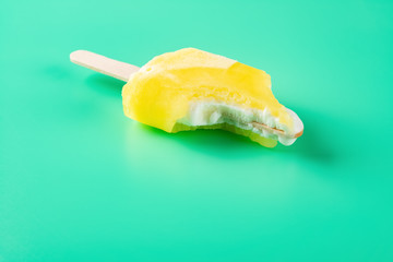 mostly eaten yellow popsicle on a light green background