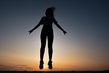 Fototapeta premium silhouette of a jumping girl on a background of dawn