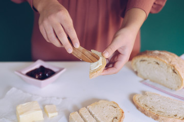 Womans hand spreads butter on homemade bread