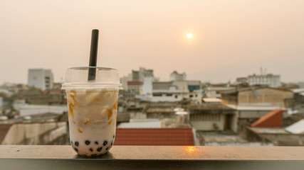 Pearl tea, iced tea on the table, background with buildings and sun