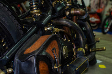 Fototapeta na wymiar WROCLAW, POLAND - August 11, 2019: USA cars show: Fragment of vintage stylish black and copper coloured engine with exhaust system pipes and side bag of restored motorcycle closeup