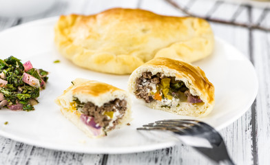 Wooden table with Empanadas (detailed close-up shot; selective focus)