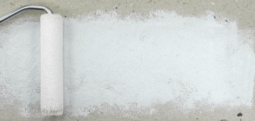 Painting a rough wall with roller. Paint roller leaving stroke of white color over a rustic background. usable for text and messages.