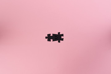 Two black connected puzzle pieces on a pink background