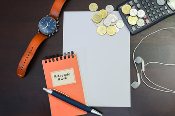 A notepad and pen with coins and calculator on a piece of blank paper isolated on a wooden background.  Work from home concept during virus spread