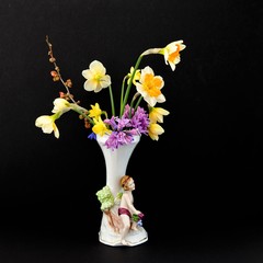Stillleben - Antike, dekorative Vase mit schönen Frühjahrsblumen vor schwarzem Hintergrund