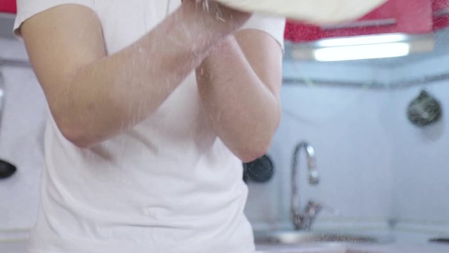 Hands of young man throw up dough