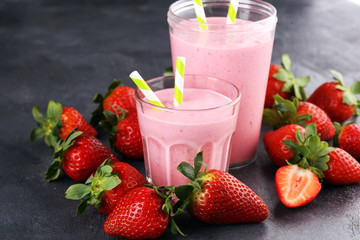 Glass of fresh strawberry shake, smoothie or milkshake and fresh strawberries on table. Healthy food and drink concept