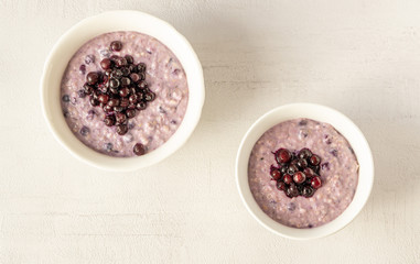 Obraz na płótnie Canvas Two oatmeal bowls with blueberries for healthy breakfast isolated on grey background. Top view. 