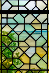 Window with stained glass, behind which the field and trees