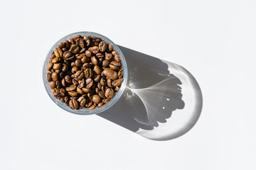 Obraz na płótnie Canvas Roasted coffee beans in transparent glass with shadow isolated on the white background. Copy space. 