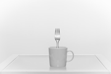 White coffee cup with a fork inside, all white
