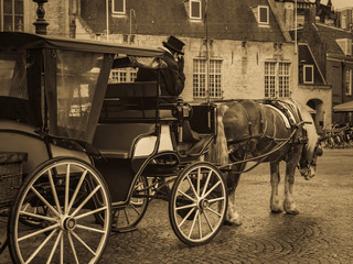 Scene in Dam Square in Amsterdam. Horses with a classic carriage and coachman as a traditional transport. Toned photo, antique style.
