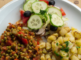 Kartoffelsalat mit sautierten Erbsen und Tomaten sowie frischer roher Gurke und Champignon