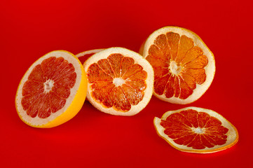 Chips of dried grapefruit sliced in thin circles, shot on a red background. Background for vegetarianism, healthy and wholesome food.