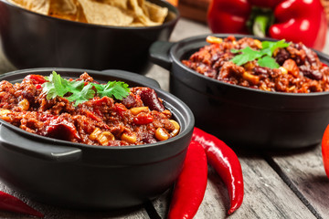 Bowls of hot chili con carne with ground beef, beans, tomatoes and corn