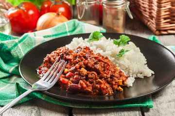 Hot chili con carne with ground beef, beans, tomatoes and corn served with rice