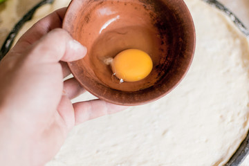Raw chicken egg in a brown clay plate.