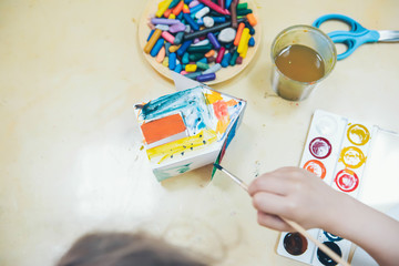 Craft lesson in kindergarten. Model of paper house glued out of paper and colored by child. Little...