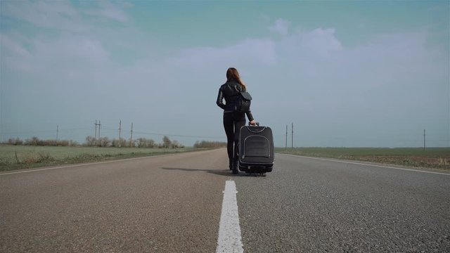 Outdoor activities travel concept woman on asphalt road with bag. Back view. Female hitchhiking around country