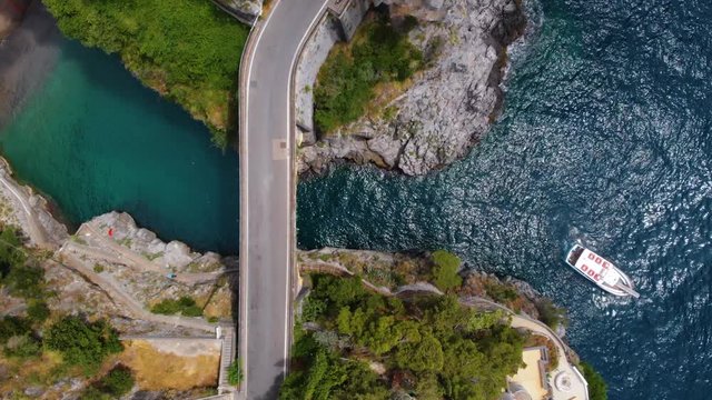 Aerial top down view of Fiordo di furore beach. Incredible beauty panorama of a paradise. The rocky seashore of southern Italy. Stone bridge and boat with tourists in clear blue water. Amalfi coast