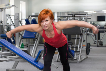 An elderly woman is engaged in power fitness in the gym.
