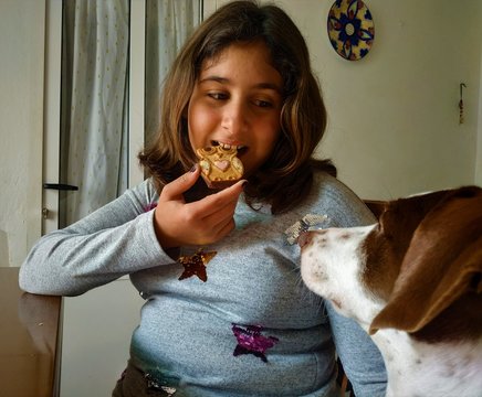 girl playing happily with her dog while eating homemade cookies at home in quarentena in April

