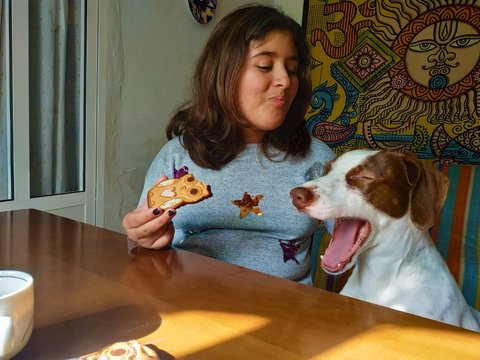 girl playing happily with her dog while eating homemade cookies at home in quarentena in April

