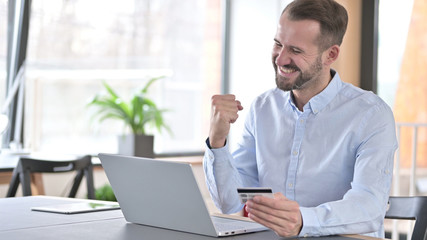 Fototapeta premium Online Payment Success by Young Man on Laptop in Office
