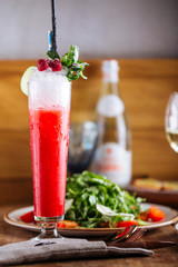 fresh red cold cocktail with crushed ice and berries, vertical, side view