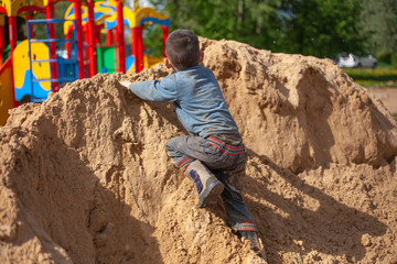 A child falls from a mountain of sand.