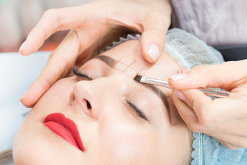 Microblading eyebrow tattoo procedure in a beauty salon for women.