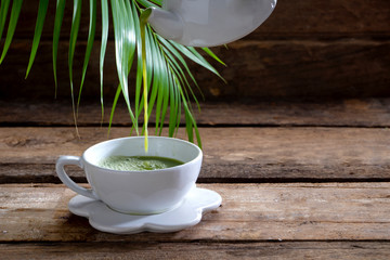 Pour green tea from the pot to a white cup