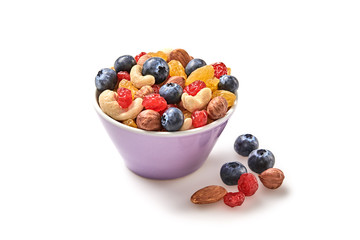 Nuts and dried fruit berries mix in bowl. Fitness diet super food. Energy cereal healthy meal. Muesli, blueberry, seeds, hazelnut, almond, oatmeal isolated on white, closeup.
