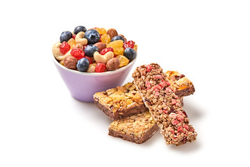 Nuts and dried fruit berries mix in bowl, granola bar. Fitness diet super food. Energy cereal healthy bar. Muesli, blueberry, seeds, hazelnut, almond, oatmeal isolated on white, closeup.