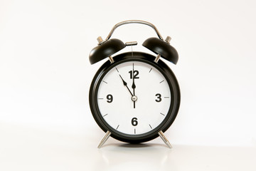 Vintage alarm clock with simple and minimalist design, isolated on white background. 5 to 12 o'clock at noon / midnight.