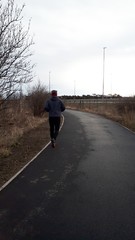 A man is Jogging on the park. Sport is a healthy lifestyle. The boy runs on an asphalt path in a park. Rear view of a running man. Copy space for your text.